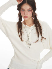 Detailed view of the star pendant necklace on a woman wearing a white ribbed knit long-sleeve shirt.