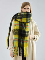 Woman wearing a yellow and black plaid scarf with fringe detail.