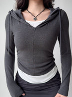 Front view of a woman in a dark grey hooded zip-up top, white tank, and black skirt, showcasing the ruched side detail.