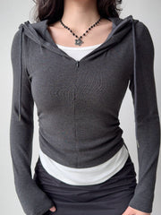 Front view of a woman in a dark grey hooded zip-up top, white tank, and black skirt, showcasing the ruched side detail.