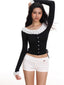 Model wearing a black off-the-shoulder long-sleeved top with white ruffled trim and white shorts.
