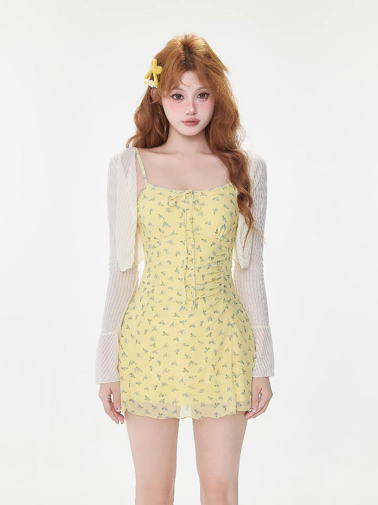 Woman wearing a yellow floral print mini dress with a white sheer cardigan, front view
