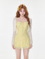 Woman wearing a yellow floral print mini dress with a white sheer cardigan, front view