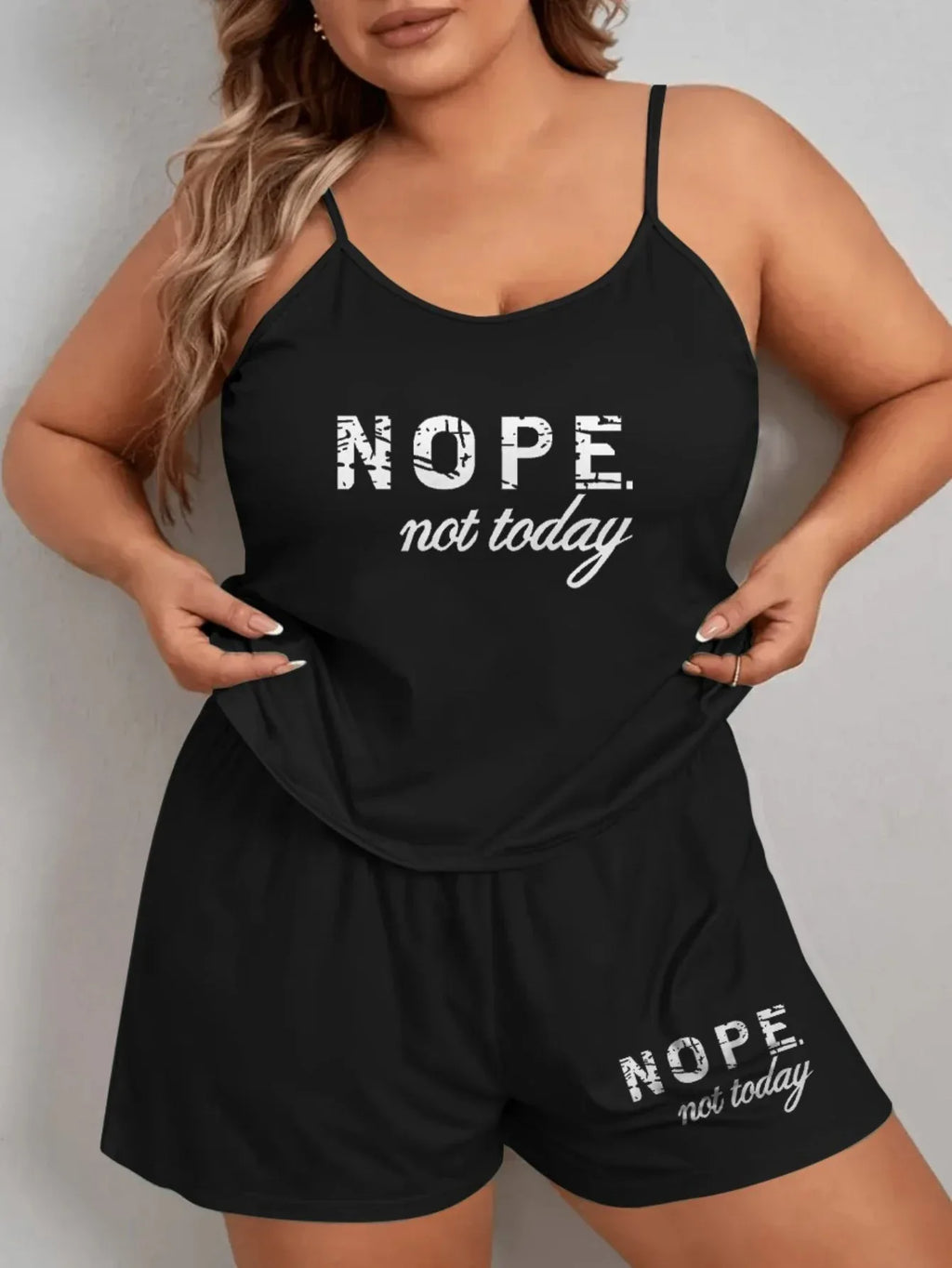 Woman in a black pajama set with 'NOPE. not today.' graphic print, adjusting the top.