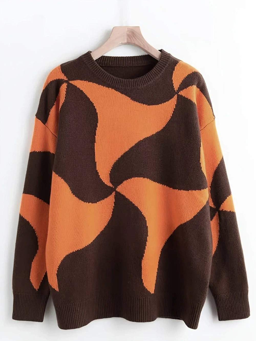 A brown and orange abstract patterned oversized sweater hanging on a wooden hanger against a white background.