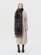 Full body shot of a woman in a beige cardigan and black scarf with white text