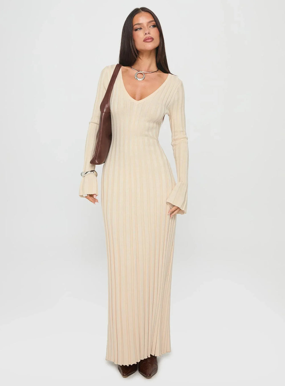 Front view of a woman modeling a cream ribbed knit maxi dress with flared cuffs and a tie waist.