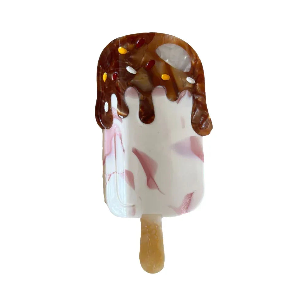 Close-up of a resin ice cream bar hair clip with chocolate drizzle and pink swirls. Main image