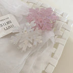 Pink and white iridescent snowflake hair clips in a white woven basket