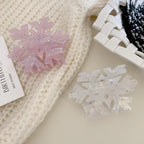 Pink and white iridescent snowflake hair clips on a white knitted sweater