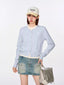 Model wearing a light blue cropped knit cardigan with a white crew neck top and a denim mini skirt.