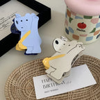 Two bear-shaped hair clips, one white and one blue, on a woven tray