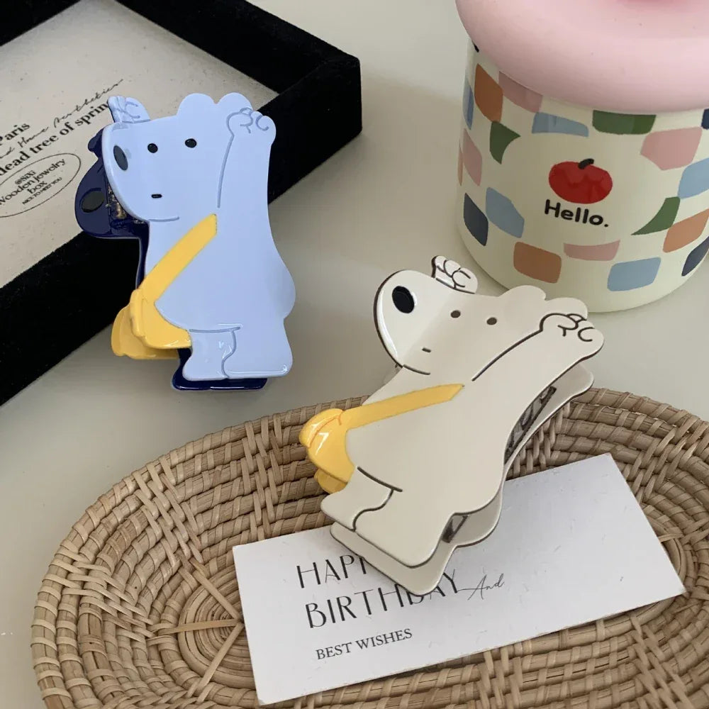 Two bear-shaped hair clips, one white and one blue, on a woven tray