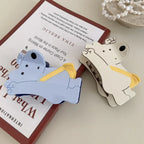 White and blue bear-shaped hair clips on top of books