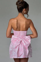 Rear view of a pink strapless mini dress with a prominent bow.