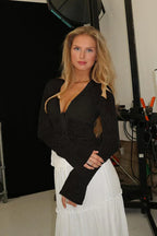 Woman wearing a black floral burnout long-sleeve top with tie-front closure and a white skirt