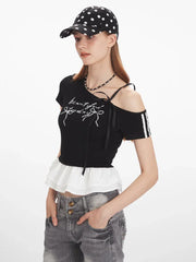 Close-up of a woman wearing a black off-the-shoulder top with graphic print and white ruffle trim.
