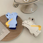 White and blue bear-shaped hair clips on a wooden coaster