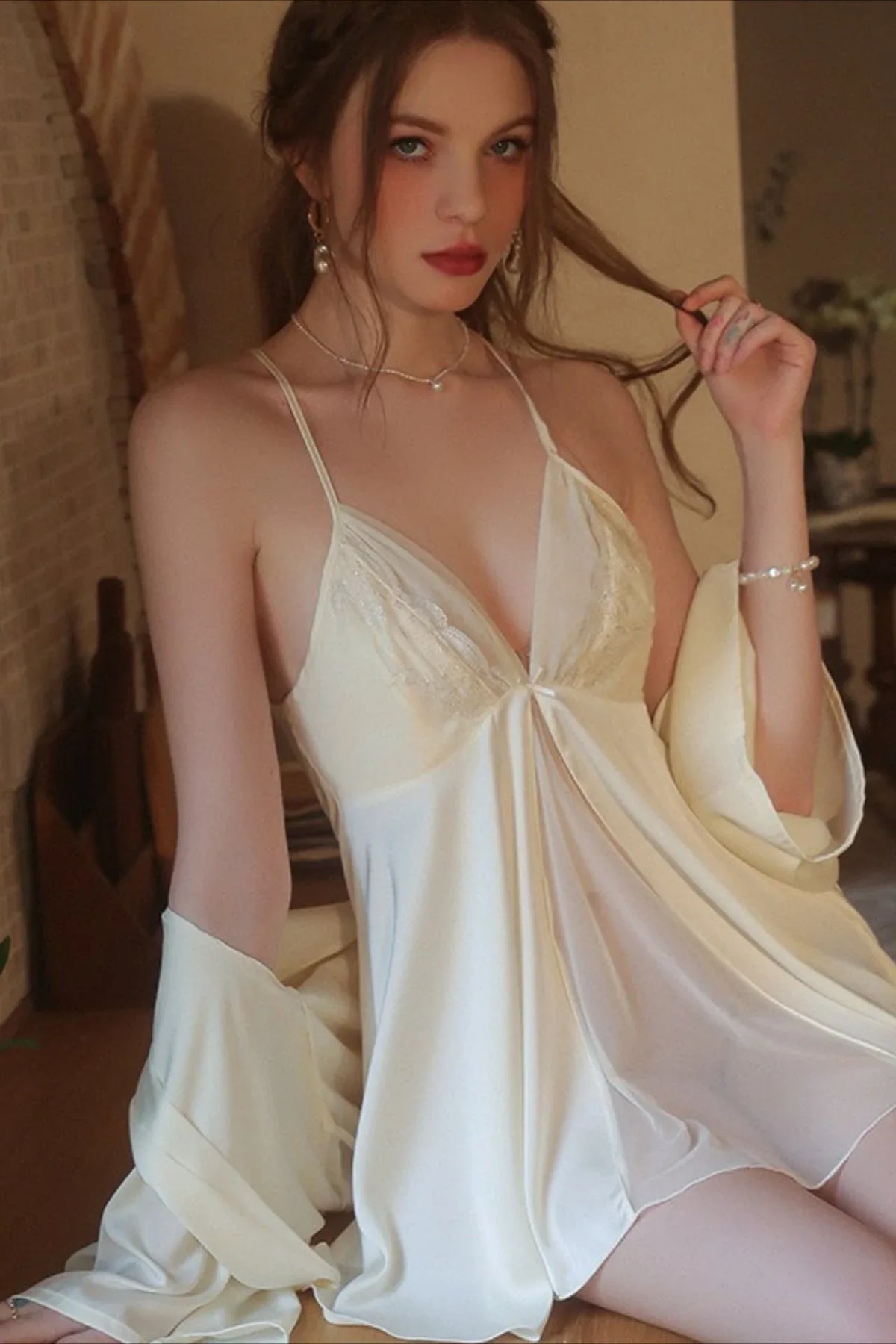 Close-up of a woman in a satin babydoll nightgown, showing the lace detailing on the bodice.