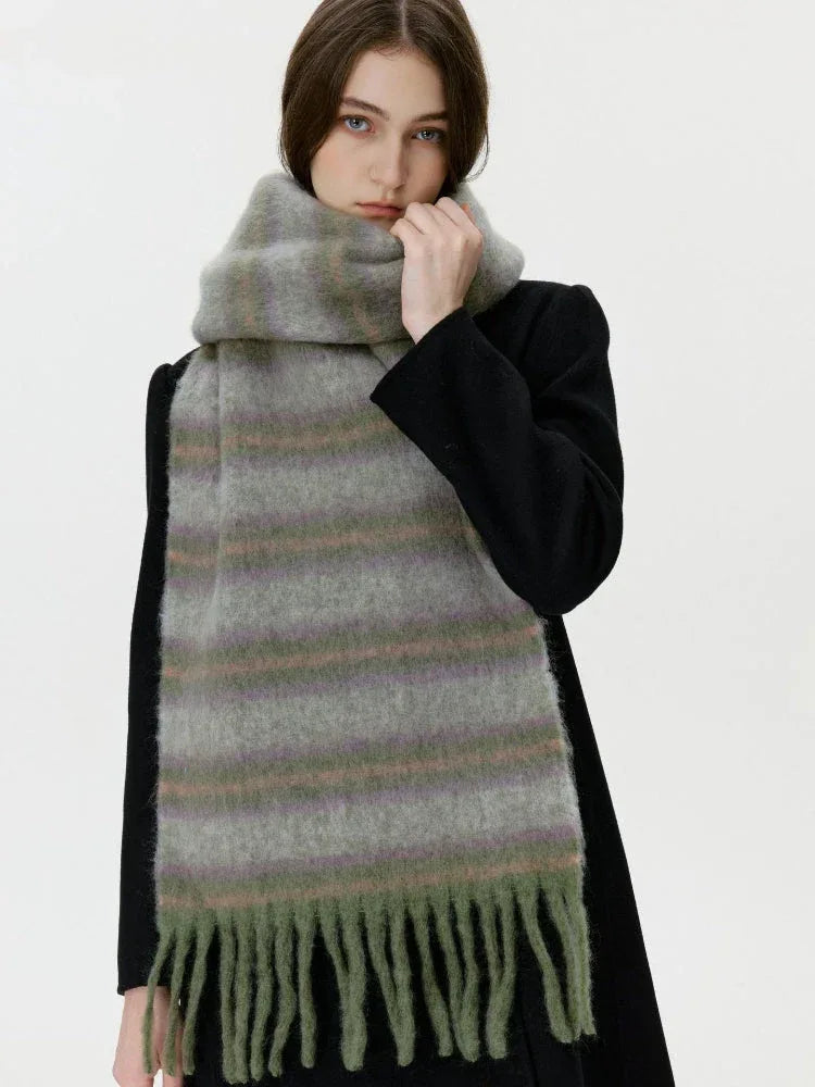 Woman wearing a black coat and a long, fuzzy, striped scarf with fringe detail.