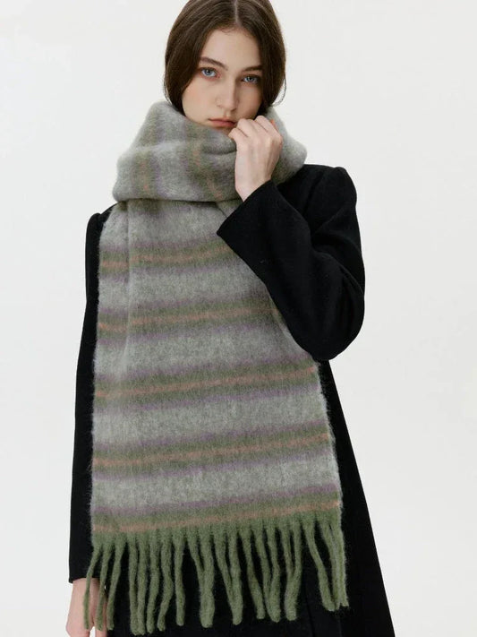 Woman wearing a black coat and a long, fuzzy, striped scarf with fringe detail.