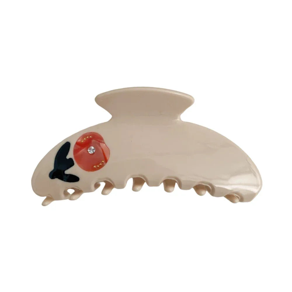 A cream-colored claw clip with a red floral design and a small gemstone. Main image