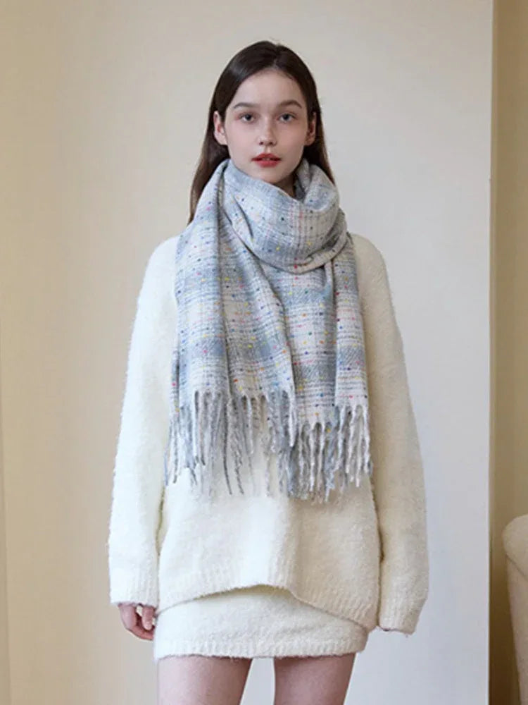 A young woman wears a light-colored, fuzzy sweater and a plaid scarf with fringe. Main image