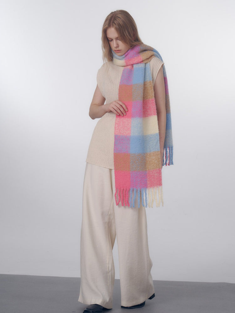 Full body shot of a woman wearing a cream-colored sleeveless top, wide-leg cream pants, and a colorful plaid scarf.