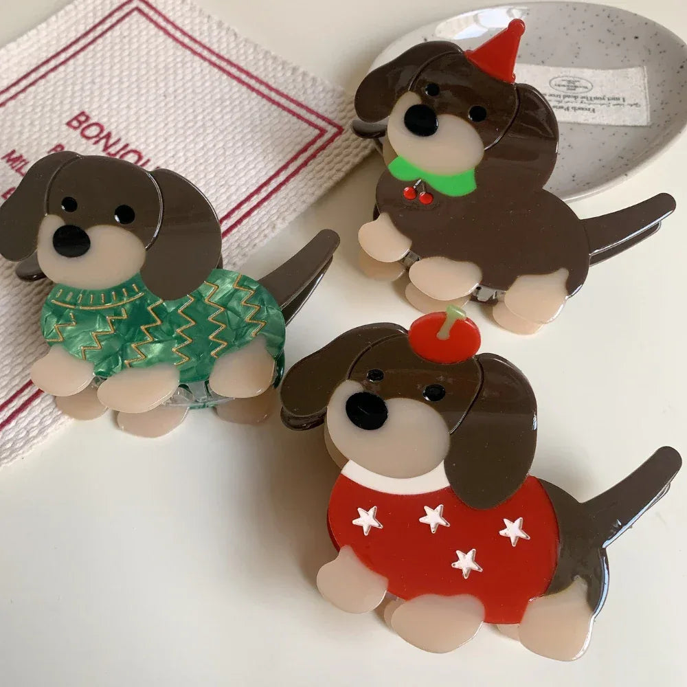 Three decorative acrylic dachshund dog brooches, each with unique holiday-themed outfits: a green sweater, a red sweater with stars, and a red party hat.