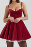Woman wearing a red velvet mini dress with lace trim and spaghetti straps.