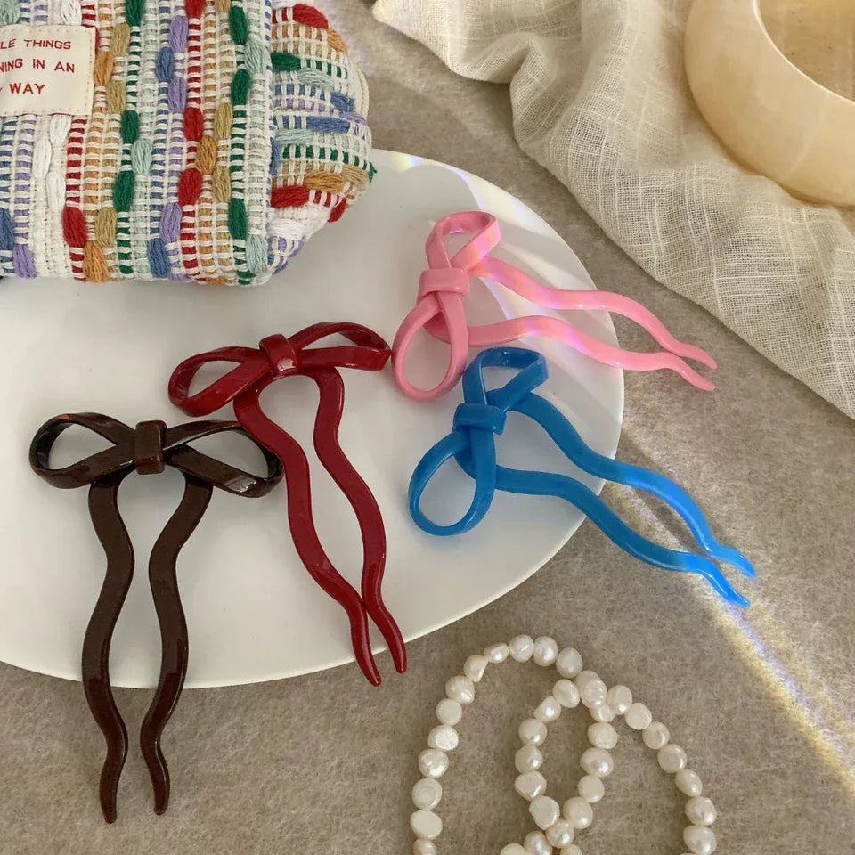 collection of colorful bow hair forks on a white plate Secondary image