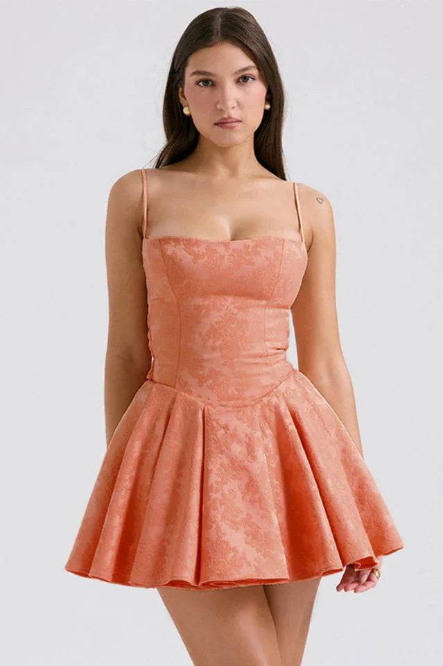 Front view of a woman wearing a coral brocade mini dress with a scuba neckline and spaghetti straps. Main image