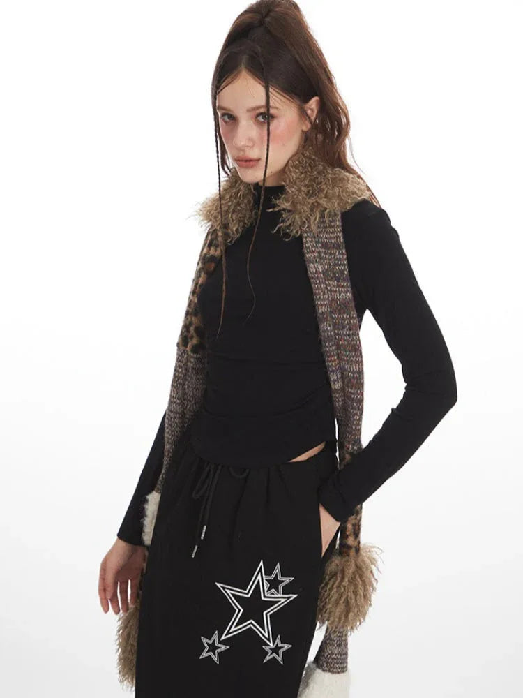 Front view of a model wearing a black long-sleeve top and a black maxi skirt with a drawstring waist and white star graphics, accessorized with a multi-patterned scarf.