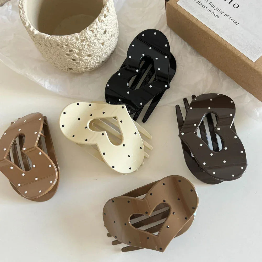 Collection of five heart-shaped hair claw clips in various colors (black, cream, brown) with white polka dots.