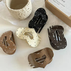 Collection of five heart-shaped hair claw clips in various colors (black, cream, brown) with white polka dots.