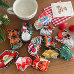 Overhead view of a variety of Christmas-themed hair claw clips, including gingerbread man, Santa, and snowman, alongside festive decorations.
