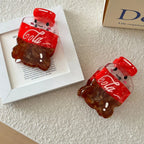 Two cute cola bottle hair clips are arranged on a white surface next to a framed picture.