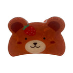 A close-up image of a glossy brown bear-shaped hair clip with a strawberry on its head.