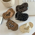 Five heart-shaped hair claw clips displayed on a white surface, featuring a polka dot design in black, cream, and brown.
