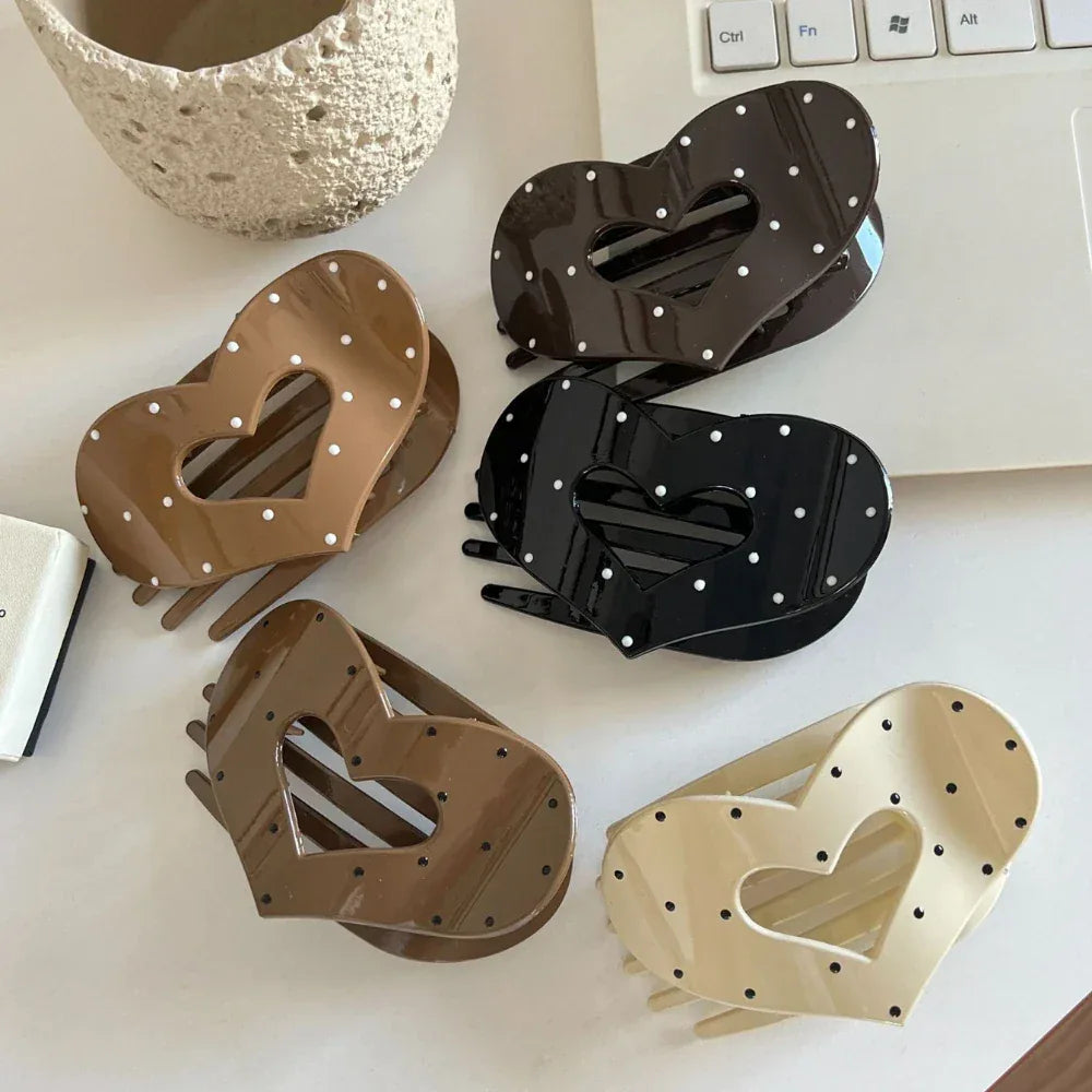 Five heart-shaped hair claw clips displayed on a white surface, featuring a polka dot design in black, cream, and brown.