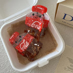 Two cute cola bottle hair clips are placed inside a white takeout container on burlap.