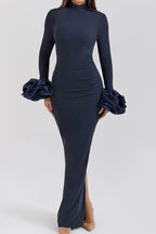 Front view of a navy blue long-sleeved column gown with ruched detailing and ruffled cuffs.