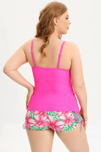 Woman wearing a bright pink ruffled tankini top with floral print swim shorts, back view.