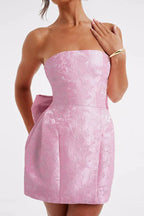 Front detail of a pink strapless dress with a textured fabric and a bow accent.
