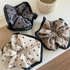 A close-up view of three scrunchies with floral patterns and contrasting trims, showcasing their textures.
