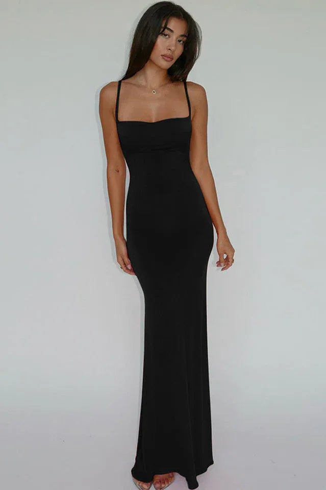 Woman wearing a black maxi dress with spaghetti straps and a square neckline.