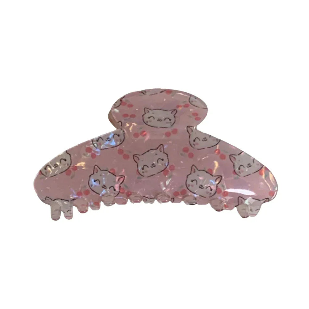 Pink claw clip with repeating cat faces and cherry blossoms.