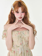 Close-up of a woman wearing a floral print dress with off-the-shoulder flutter sleeves.