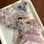 A collection of various cat-themed claw clips arranged on a white tray.