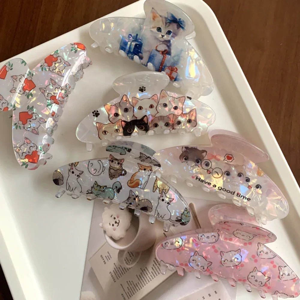 A collection of various cat-themed claw clips arranged on a white tray.